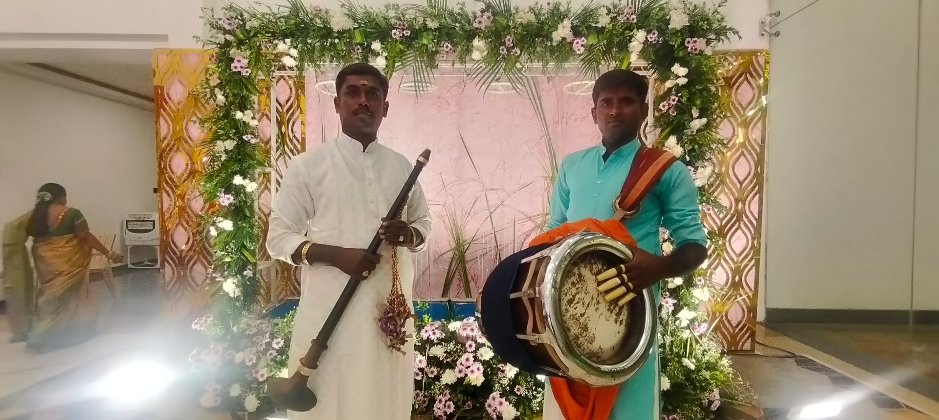 Tambura and Thavil artists beneath floral wedding arch